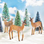 Three toy deer figurines in snow
