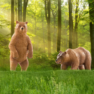 Two toy grizzly bear figurines in forest