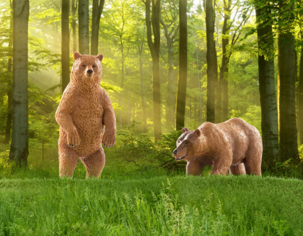 Two toy grizzly bear figurines in forest