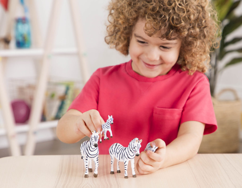 young boy playing with toy zebras.