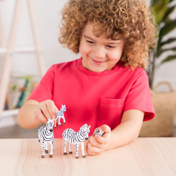 Kid playing with toy zebra figurines