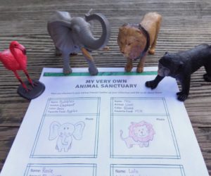 toy flamingo, elephant, lion, and monkey on desk with sheet of paper.