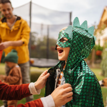 Child dressed as a dragon for Halloween outside with his parents